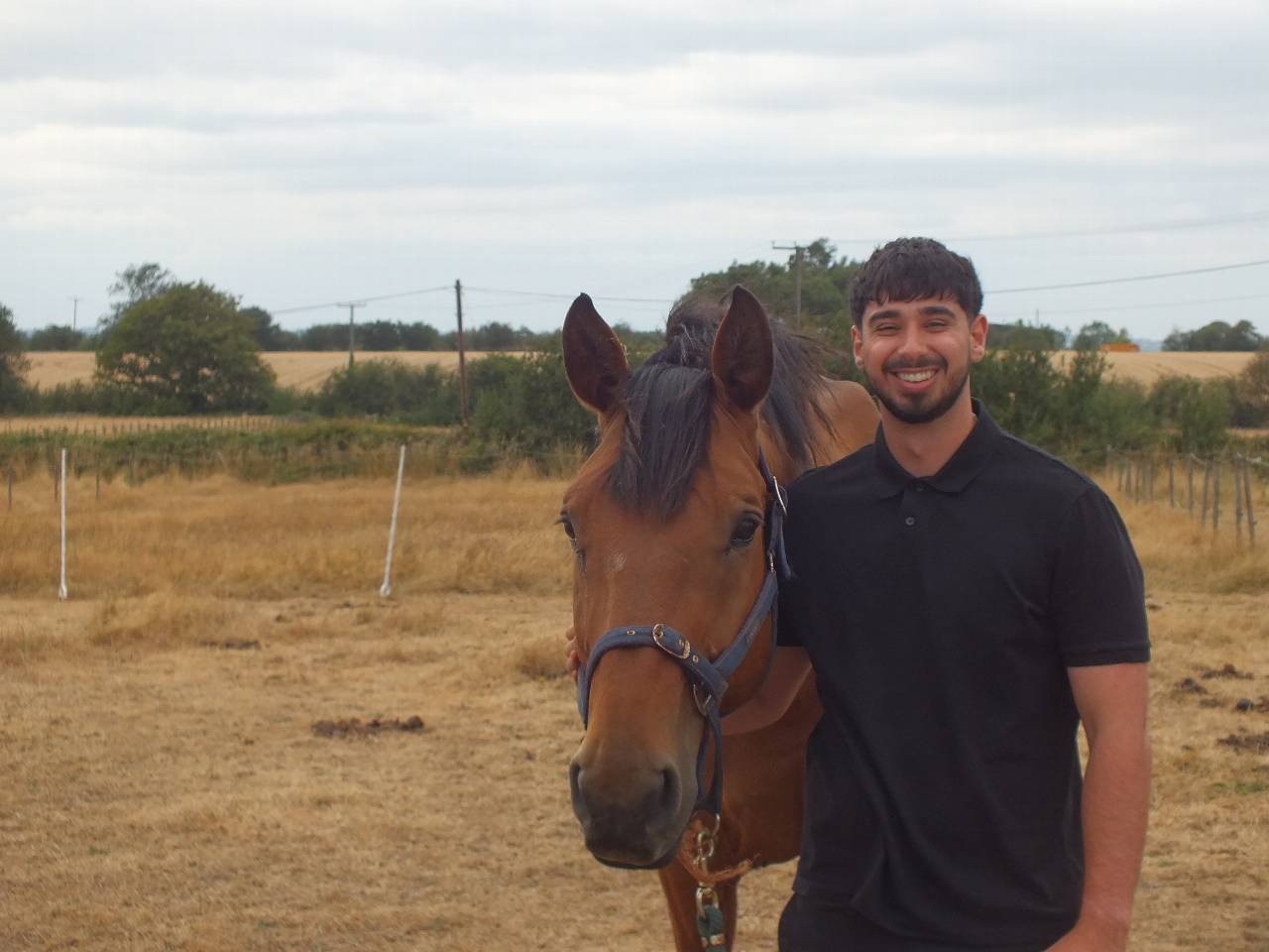 Student smiling stood next to a horse