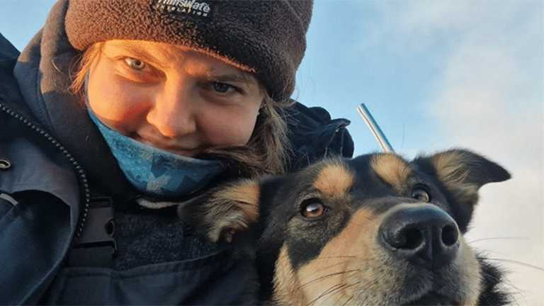 A woman - Jessiica Walker - in a wooly hat with a dog