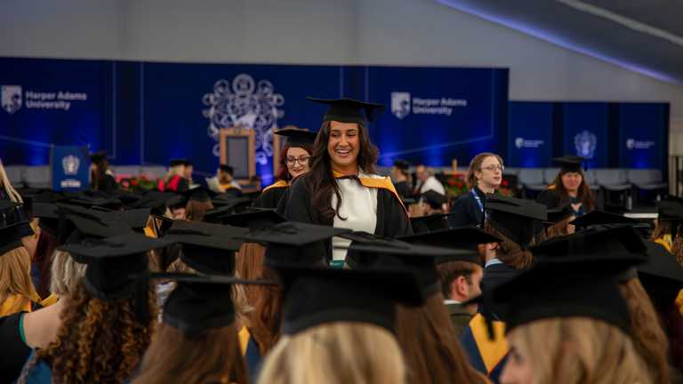 A student smiles at friends as they wait to graduate