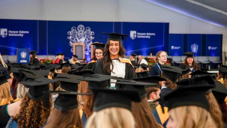 A student smiles at friends as they wait to graduate