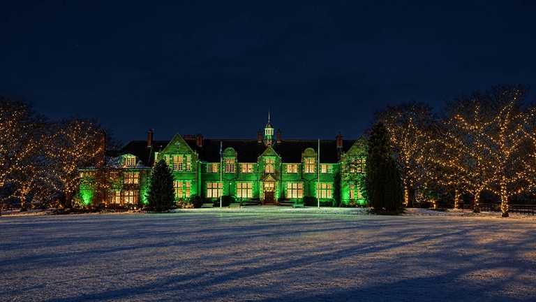 Harper Adams University's Foundation House lit up green in a snowy atmosphere