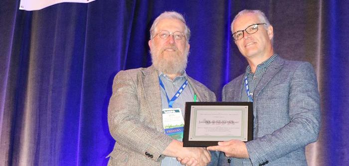 Professor James Lowenberg-DeBoer is congratulated by the out-going ISPA president Nicolas Tremblay. 