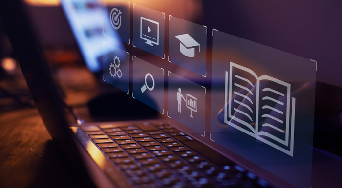 Image shows a computer with projected icons suggestive of learning: charts, a book and a person in a graduation cap