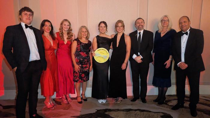 Emma Burgess holds her award flanked by fellow graduates, students and lecturers